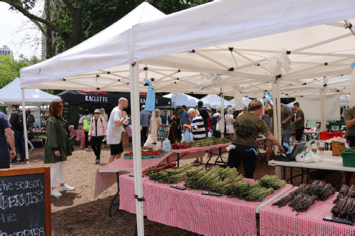 One stall displays a large quantity of asparagus laid out on tablecloths.