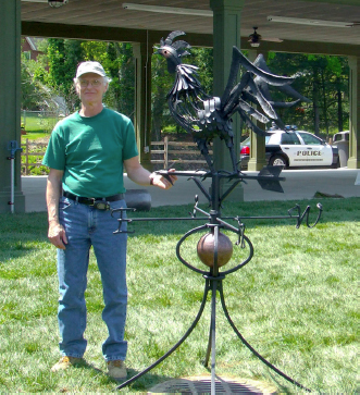Bill Gable stands by the metal weathervane he crafted. The weathervane is as tall as him.