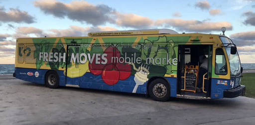 A converted transit bus with produce items painted on it. The side of it also reads, “Fresh Moves Mobile Market.”