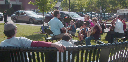 Renaissance Music Academy musicians play at the farmers market. A man sits on a bench listening.